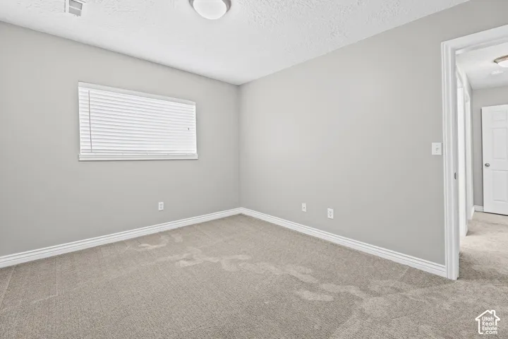 Recessed window with horizontal blinds, neutral wall paint, and light-toned carpet flooring