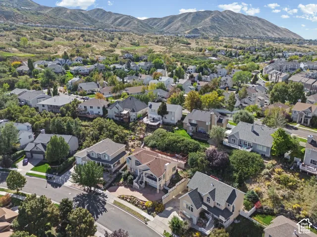 Residential neighborhood with mature trees, established landscaping, and mountain backdrop