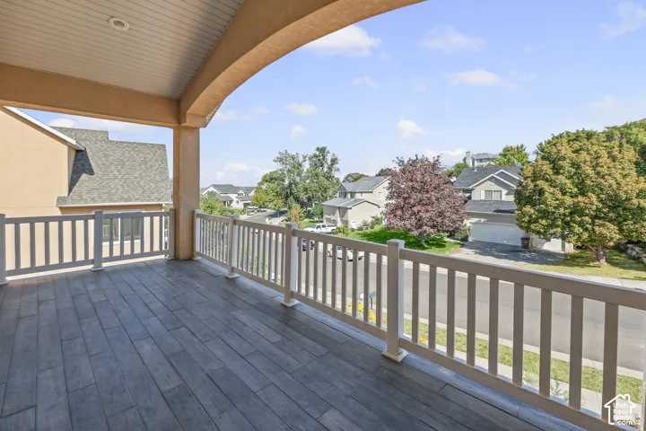 Covered balcony with wood-finish flooring and white railing