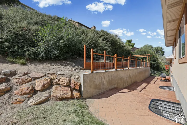 Stamped concrete patio, concrete retaining wall, wood and wire fence, natural rock landscaping, and mature hillside plantings