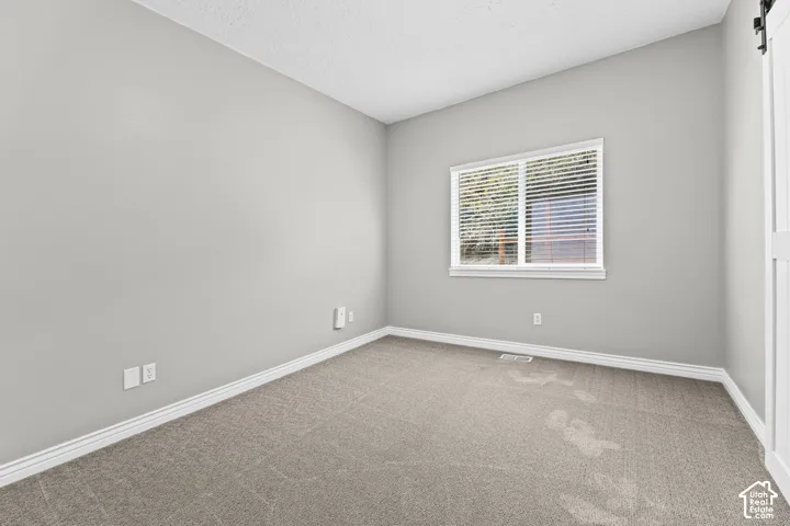 Light gray wall paint, white trim, window with blinds, and gray carpet