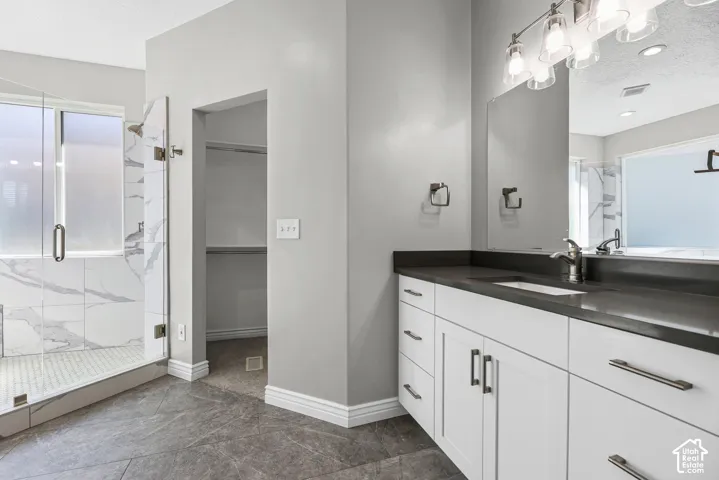 Walk-in shower with clear glass enclosure and white marble-patterned tile