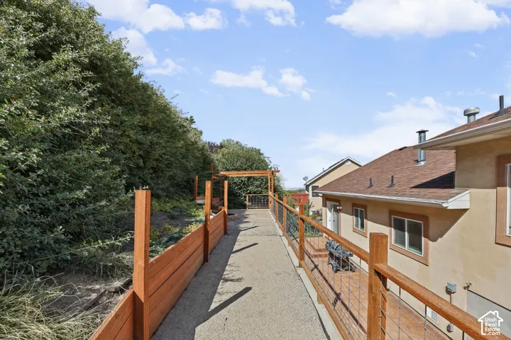 Exterior walkway featuring wood-tone railings with metal infill, leading to a wood-tone pergola