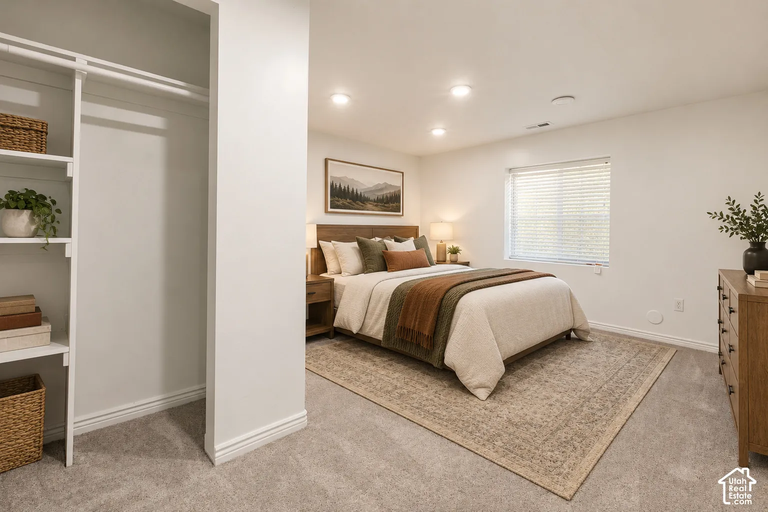 Built-in closet shelving, recessed ceiling lighting, wall-to-wall carpeting, wood-finish headboard, and window with blinds