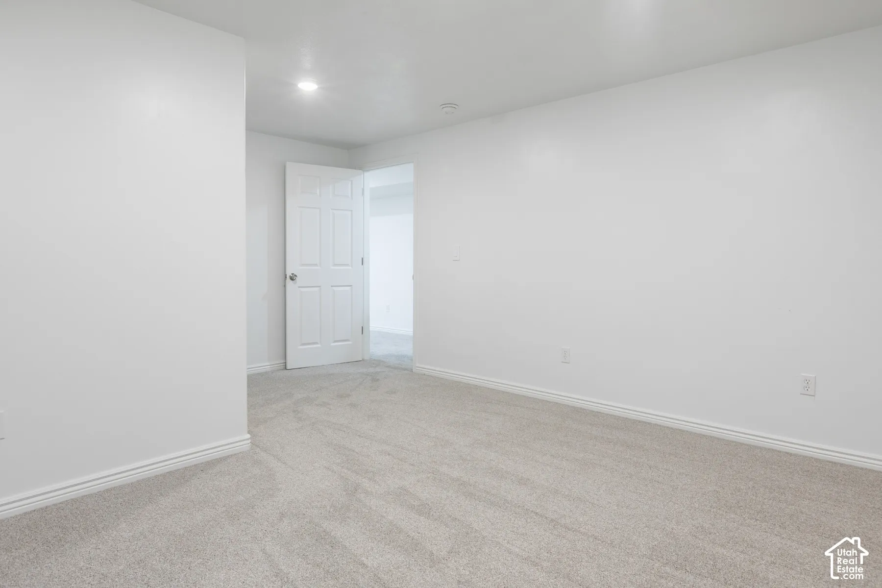 Neutral toned carpet flooring, white walls, recessed ceiling lighting, and a paneled door