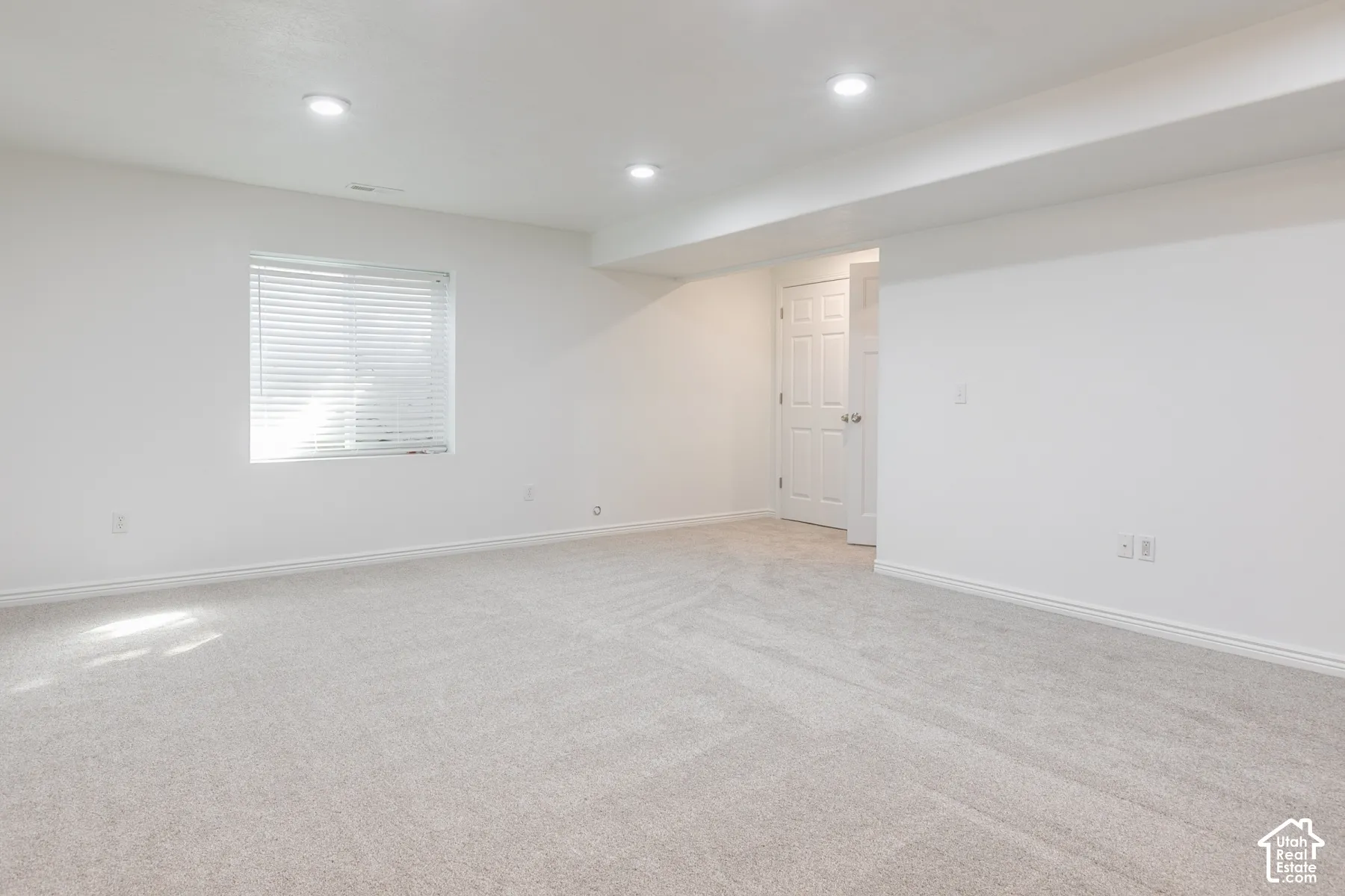 Plush carpet flooring, recessed lighting, white walls, and a window with blinds