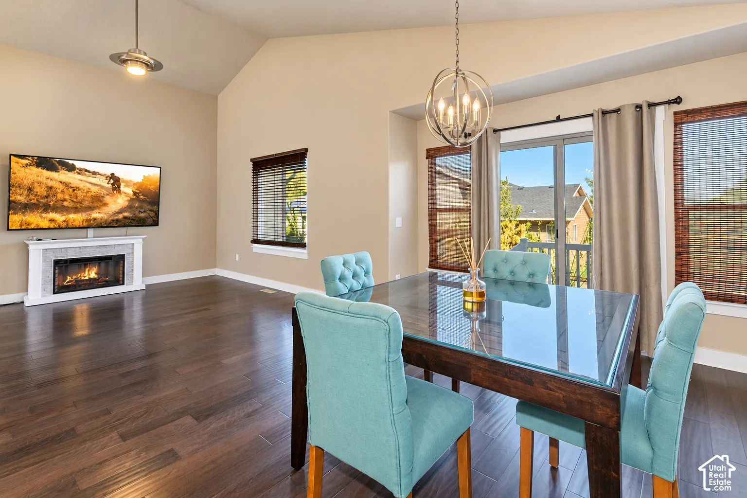 Vaulted ceilings, wood-finish flooring, a fireplace with a tiled surround, and a glass-paneled patio door