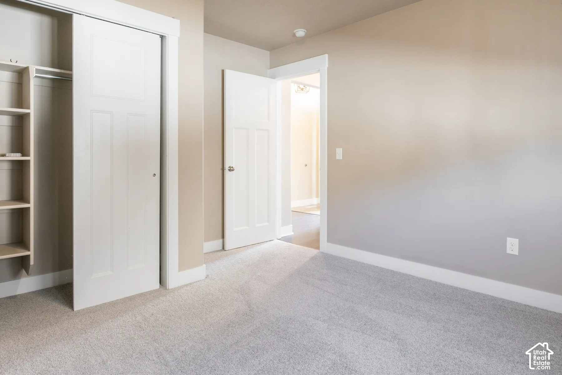 Built-in closet shelving, sliding panel closet doors, neutral wall paint, carpeted flooring, and white trim