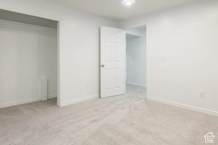 Plush carpet flooring, recessed ceiling lighting, crisp white walls, and a built-in closet with hanging rod