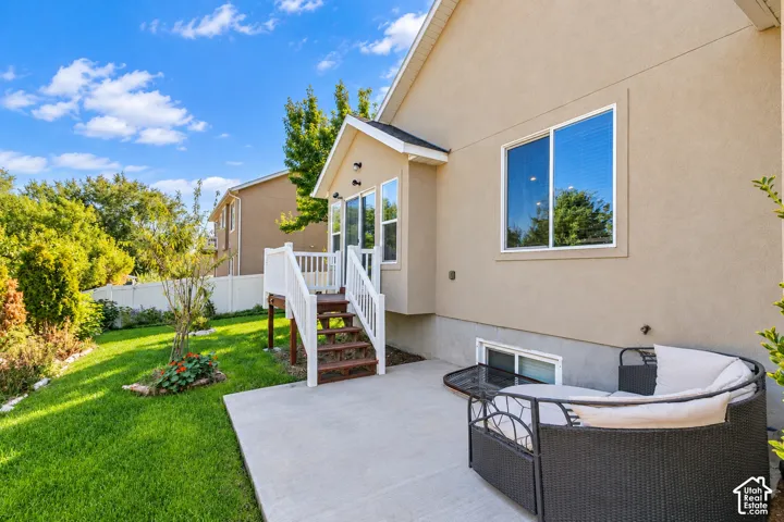 Expansive backyard featuring a manicured lawn, concrete patio, and mature trees