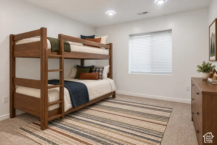 Recessed lighting, window with blinds, wood-finish dresser with dark hardware, and carpet flooring