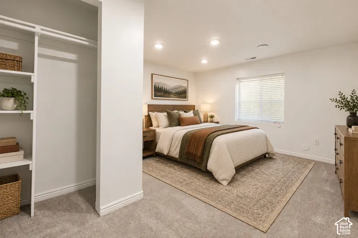 Built-in closet shelving, recessed ceiling lighting, wall-to-wall carpeting, wood-finish headboard, and window with blinds