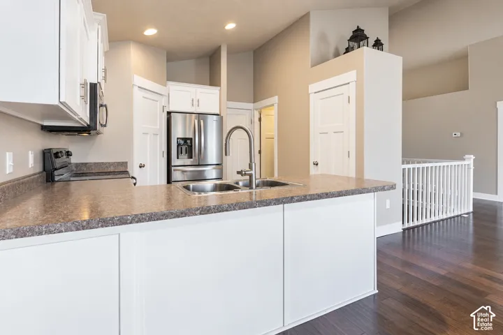 Kitchen featuring white cabinetry, stainless steel appliances, a double basin sink, and a spacious countertop