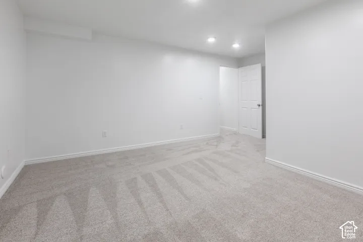Recessed lighting illuminates neutral carpeting and white walls