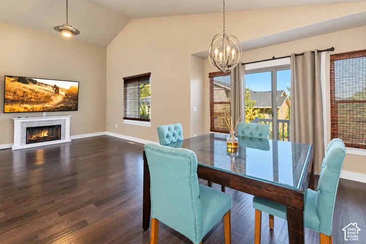 Vaulted ceilings, wood-finish flooring, a fireplace with a tiled surround, and a glass-paneled patio door