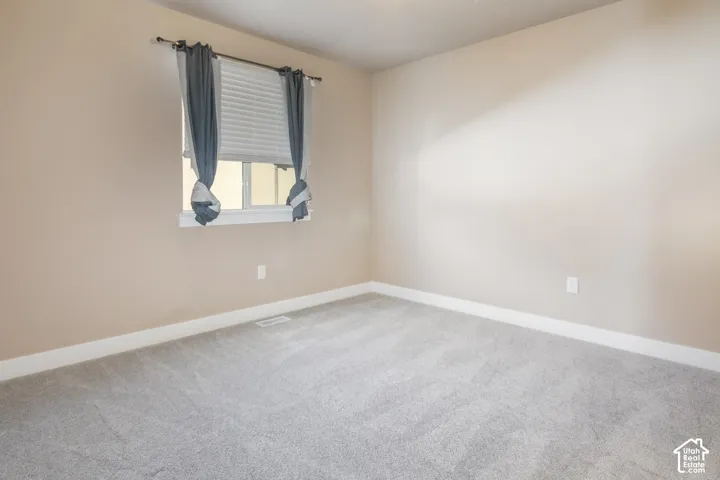 Window with horizontal blinds, neutral wall paint, white trim, and light-toned carpeting