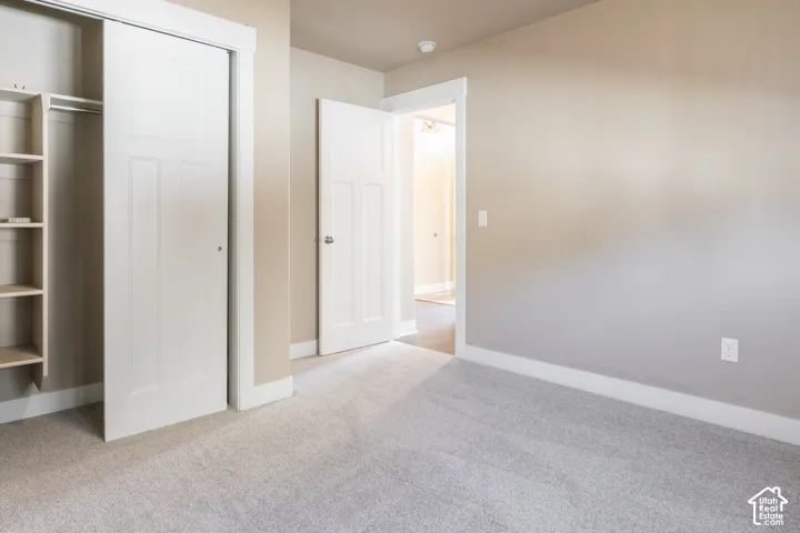 Built-in closet shelving, sliding panel closet doors, neutral wall paint, carpeted flooring, and white trim