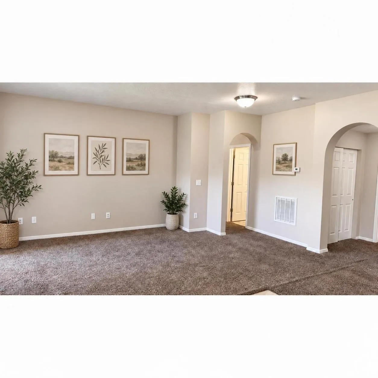 Neutral-toned interior space featuring textured wall-to-wall carpeting, dual arched architectural doorways, and recessed lighting fixtures
