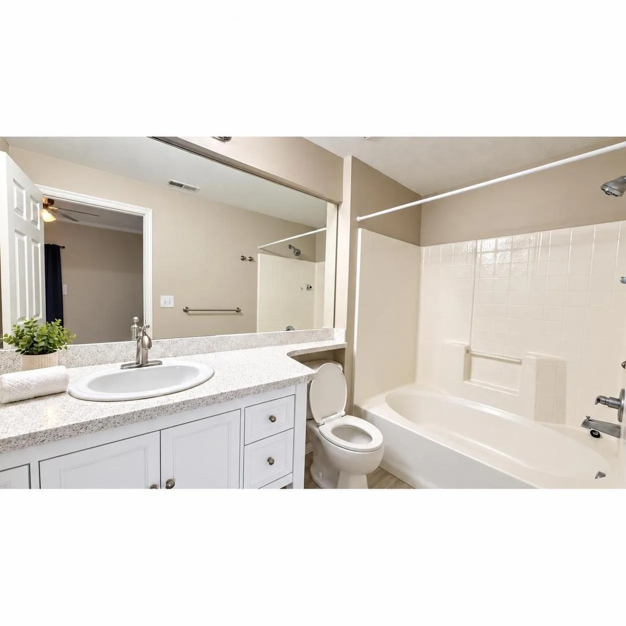 Primary Bathroom: Vanity with white cabinetry and integrated sink, large mirror, and full-size bathtub with shower combination