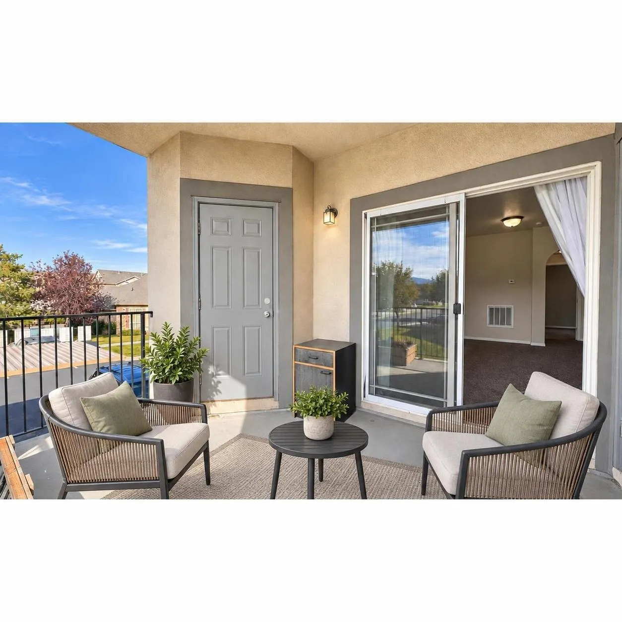 Covered balcony featuring concrete flooring, black metal railing, sliding glass door entry, and wall-mounted exterior lighting