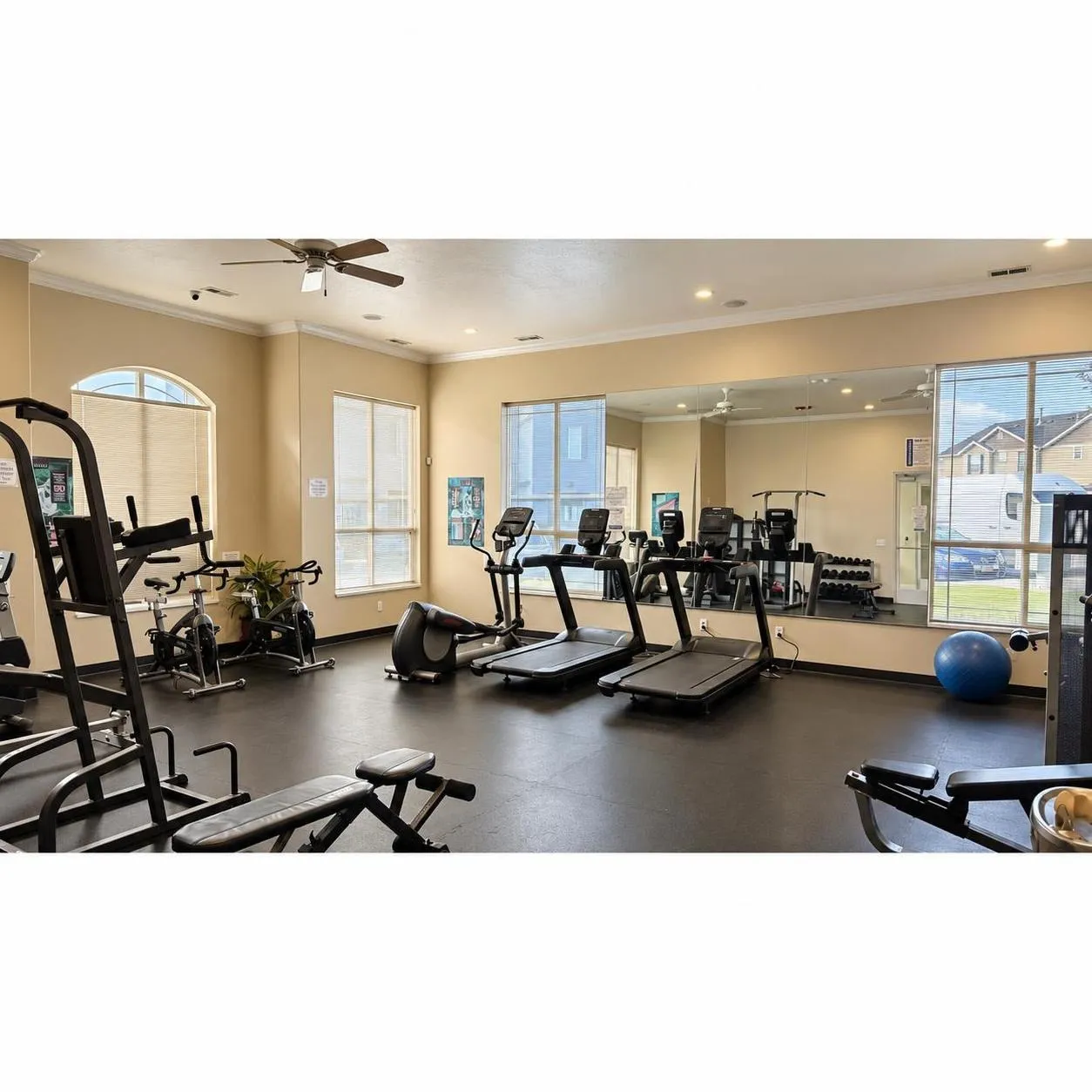 Dedicated fitness area with rubber flooring, large windows, and a full-wall mirror