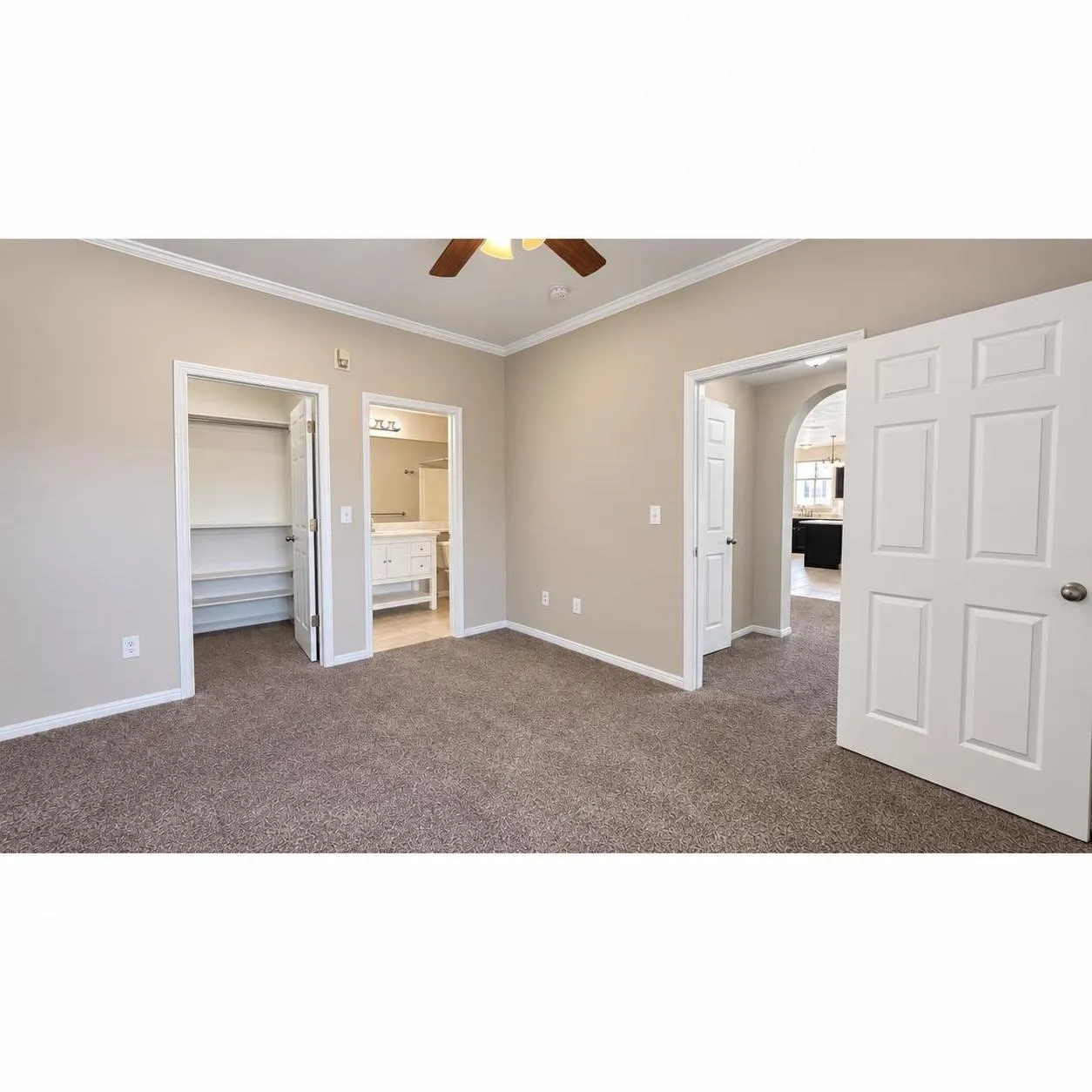 Primary Bedroom: Plush carpeted flooring, a ceiling fan with wood-finish blades, and crown molding