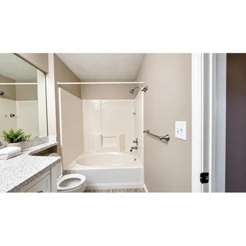 Primary Bathroom: Full bathroom featuring a shower/tub combination, single vanity with a speckled countertop, and wood-finish flooring
