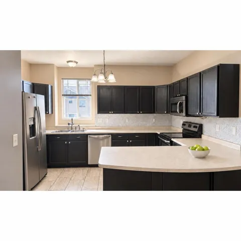 Kitchen featuring dark cabinetry, light-toned countertops, stainless steel appliances, and tiled flooring
