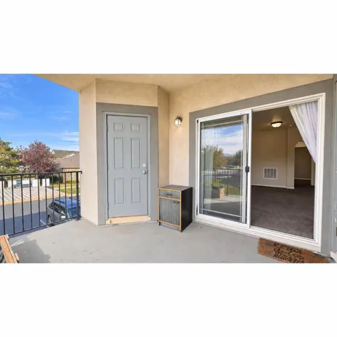 Balcony with concrete flooring, black metal railing, and exterior wall sconce