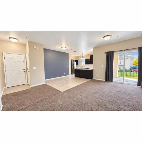 Expansive living area with brown carpet flooring, light-toned wall paint, and recessed lighting