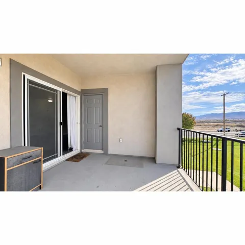 Patio featuring a sliding glass door, an exterior door, a black metal railing, and a concrete surface