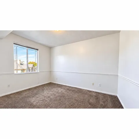Bedroom 2 with white walls, a large window, and decorative trim
