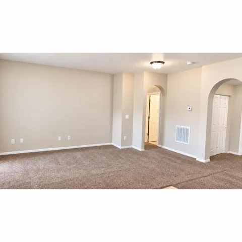 Neutral-toned carpet flooring, arched doorways, a flush mount ceiling light fixture, and white trim