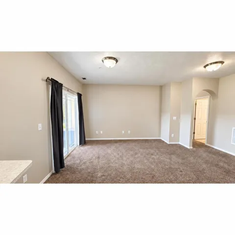 Spacious room featuring neutral wall tones and plush carpeting