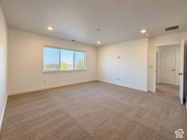 Carpeted room with recessed lighting, multiple windows, white trim, and a white interior door