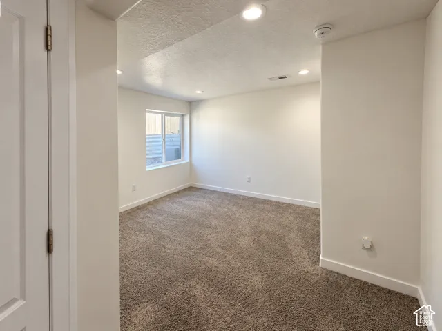Neutral wall paint, recessed lighting, carpet flooring, and a single window