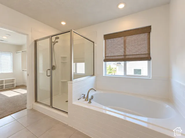 Built-in soaking tub with brushed nickel fixtures, glass-enclosed shower, and recessed lighting