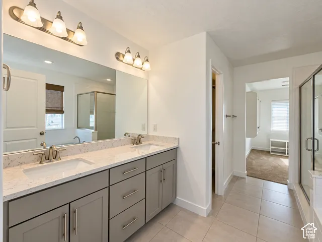 Dual vanity with light gray cabinetry and brushed nickel hardware, expansive countertop space, large wall mirror, and tile flooring