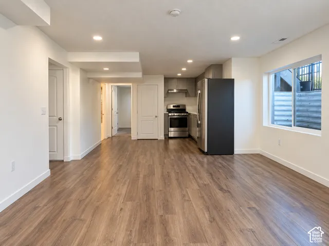 Recessed lighting, wood-finish flooring, white walls, stainless steel appliances, and a window