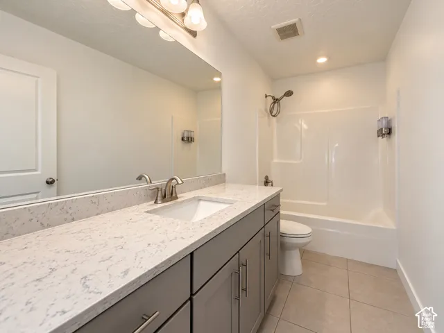 Quartz countertop, dual-basin vanity, recessed lighting, brushed nickel fixtures, and a shower-over-tub combination