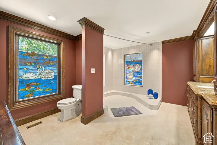 Custom stained-glass window, extensive wood trim, built-in vanity with stone countertop, white tiled shower, and recessed lighting
