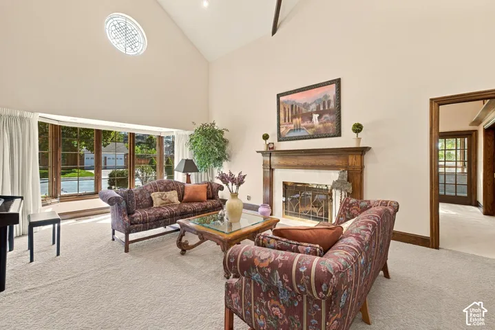 Vaulted ceilings with an arched window, a fireplace with a wood mantel, a bay window, and a light-toned carpet