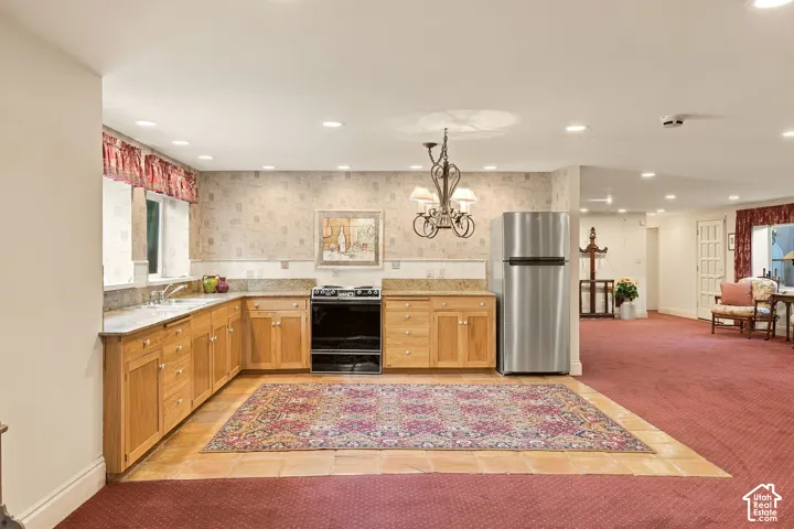 L-shaped kitchen with wood cabinetry, light-toned countertops, and a full-size stainless steel refrigerator