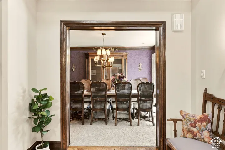 Hardwood framed entryway opening to a dining area featuring patterned wallpaper and a chandelier