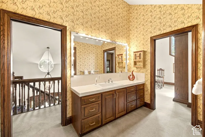 Vanity with integrated sink, wood-finish cabinetry, and overhead lighting