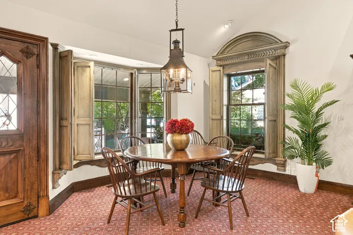 Bay window with custom wood shutters, arched window with detailed trim, ornate wood entry door with leaded glass, recessed ceiling lighting, and a prominent hanging light fixture