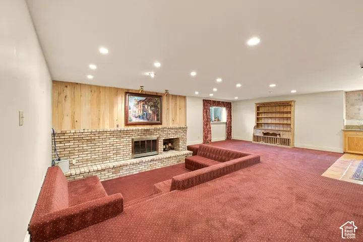 Recessed lighting illuminates a spacious room featuring a brick fireplace with a wood mantel