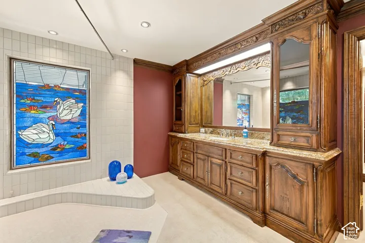 Spa-inspired primary bathroom showcasing custom wood cabinetry with marble countertops, dual vanity with integrated mirrors, white subway tile surround, and recessed ceiling lighting