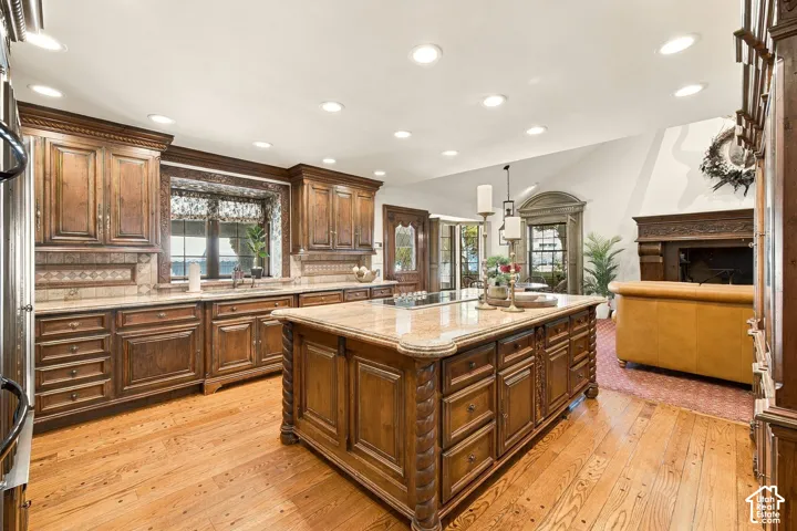 Hardwood flooring, custom wood cabinetry, stone countertops, built-in island cooktop, and recessed lighting