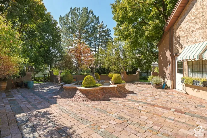 Hardscaped patio featuring multi-toned pavers, built-in planter beds, and a tiered fountain